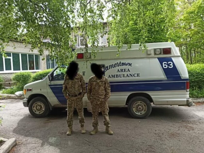 Uniformed soliders stand in front of a van-style ambulance that says "Jamestown Area Ambulance."