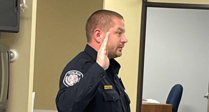 An officer raises his right hand during an oath of office