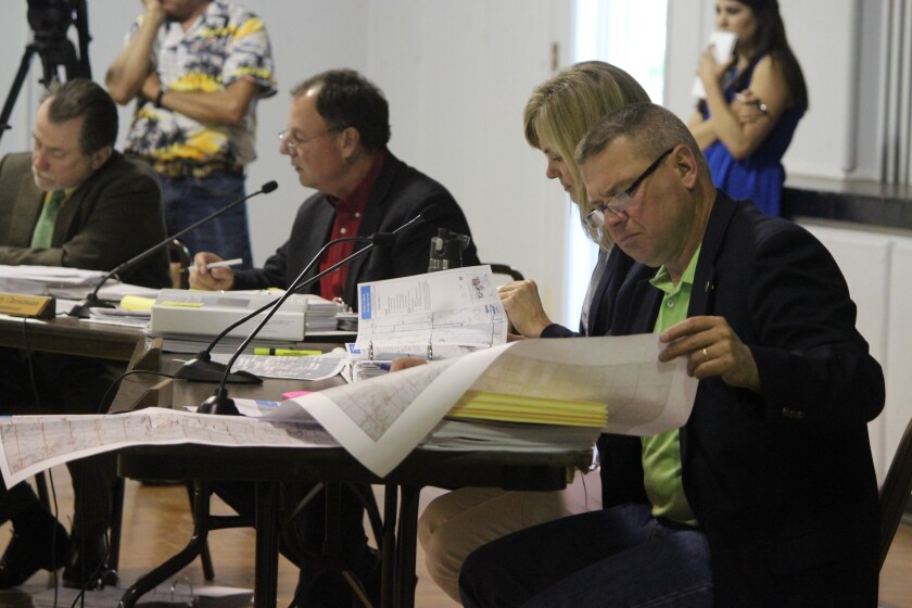 The Public Service Commission held a hearing for the proposed Brady Wind II in New England on Tuesday. Left, Commissioner Randy Christmann, Chairman Julie Fedorchak and Brian Kalk look at exhibits presented by NextEra. (Press Photo by Kalsey Stults)