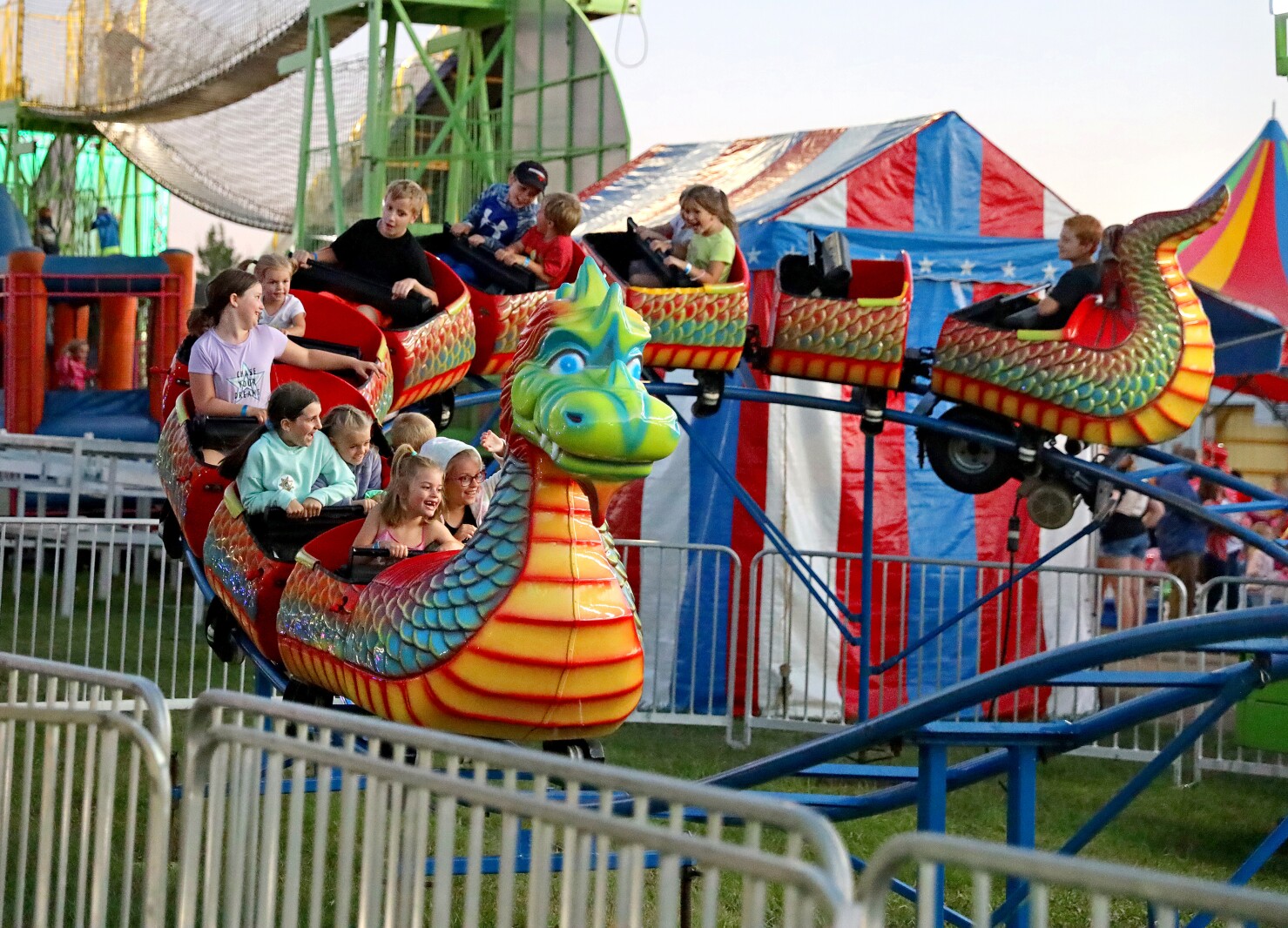 Kids ride a dragon roller coaster at the fair