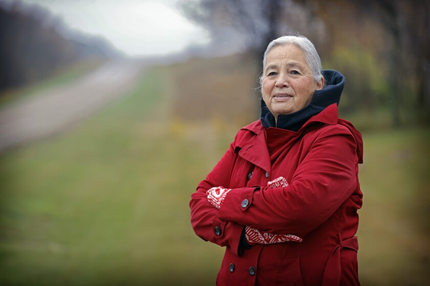 A woman in a red coat and matching mittens poses with crossed arms.