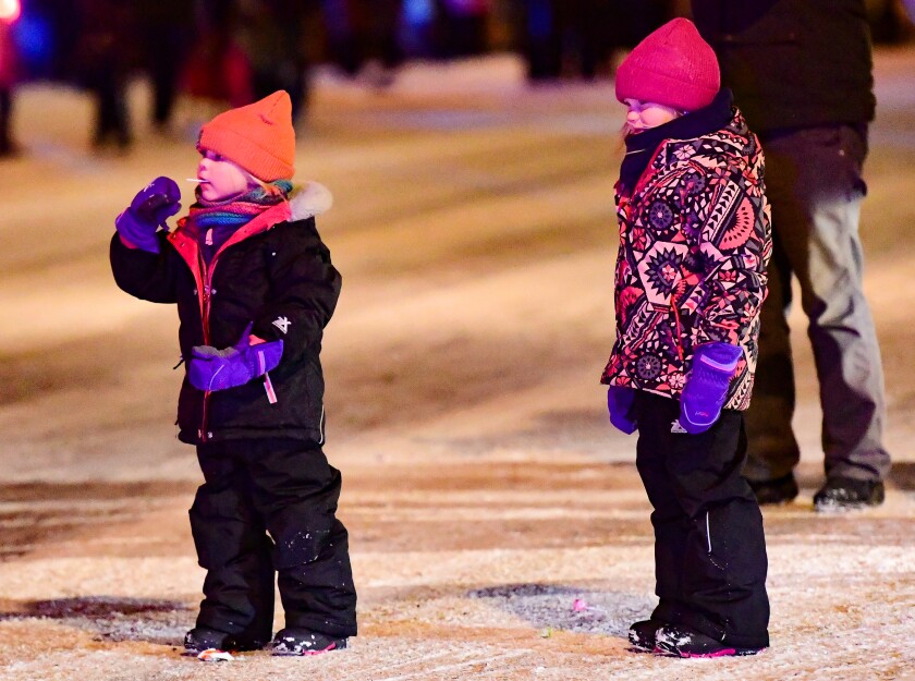 Two little girls look down the street in anticipation of Santa