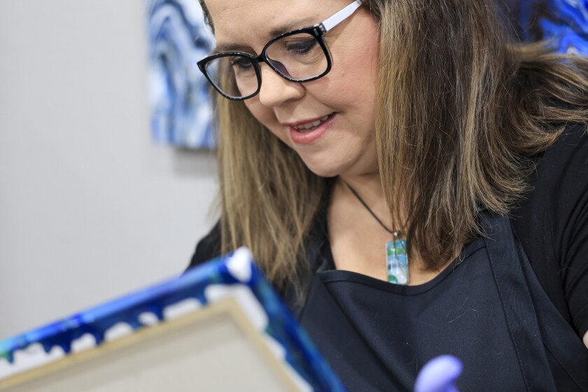 woman create fuid art work using paint