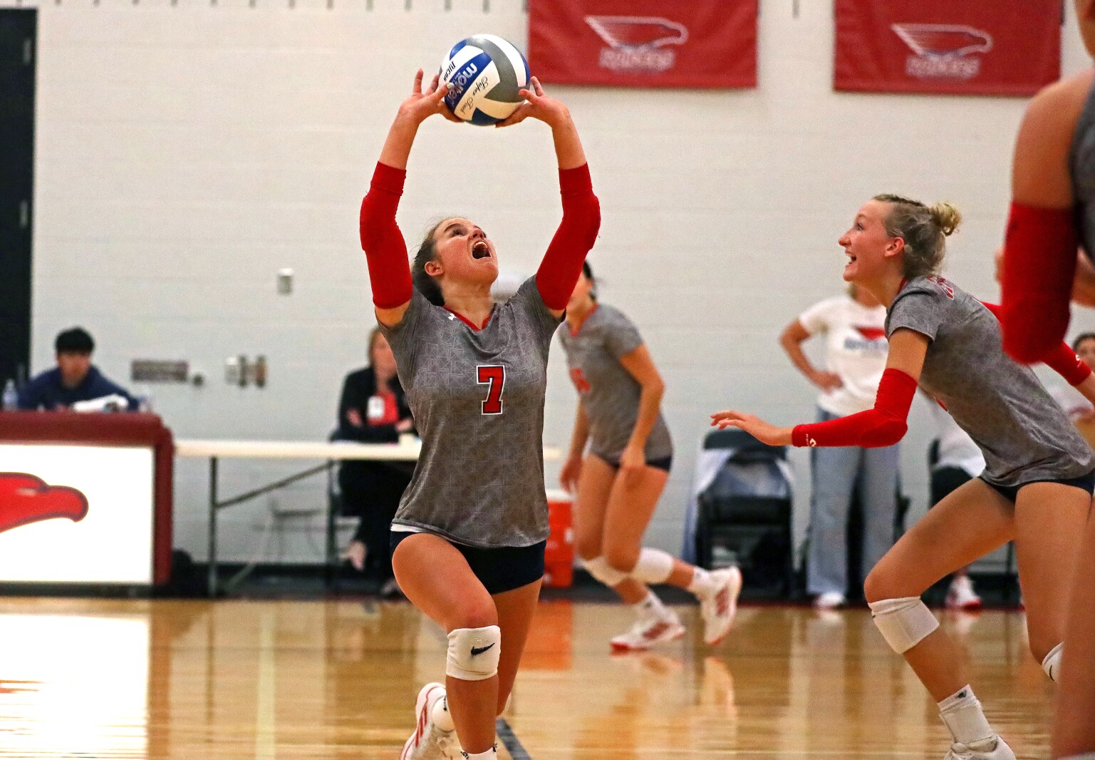 A player sets the ball as another player watches.