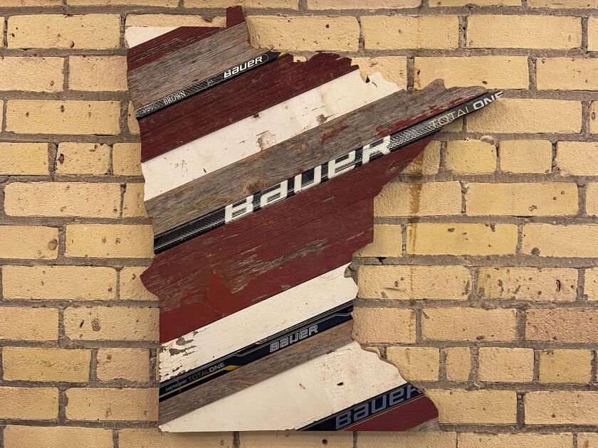 A wall decor in the shape of the state of Minnesota, made from reclaimed wood, including Bauer hockey sticks.