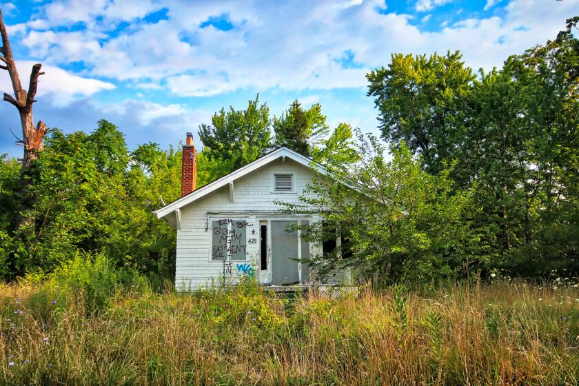 A single-residence home by itself in an area with overgrown grass and weeds.