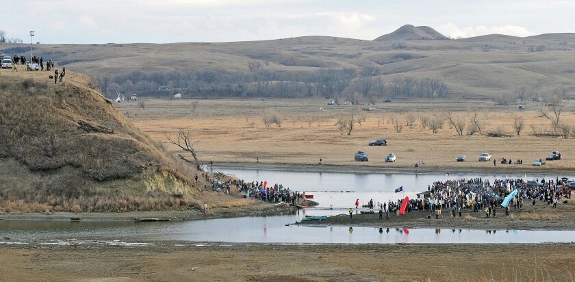 Law enforcement stand atop Turtle Hill on the Cannonball Ranch watching as protesters stand at the base while others stand across the water on Thursday afternoon, Nov. 24, 2016, in southern Morton County. A makeshift bridge placed by the protesters allowed them access to the private property. TOM STROMME/Bismarck Tribune