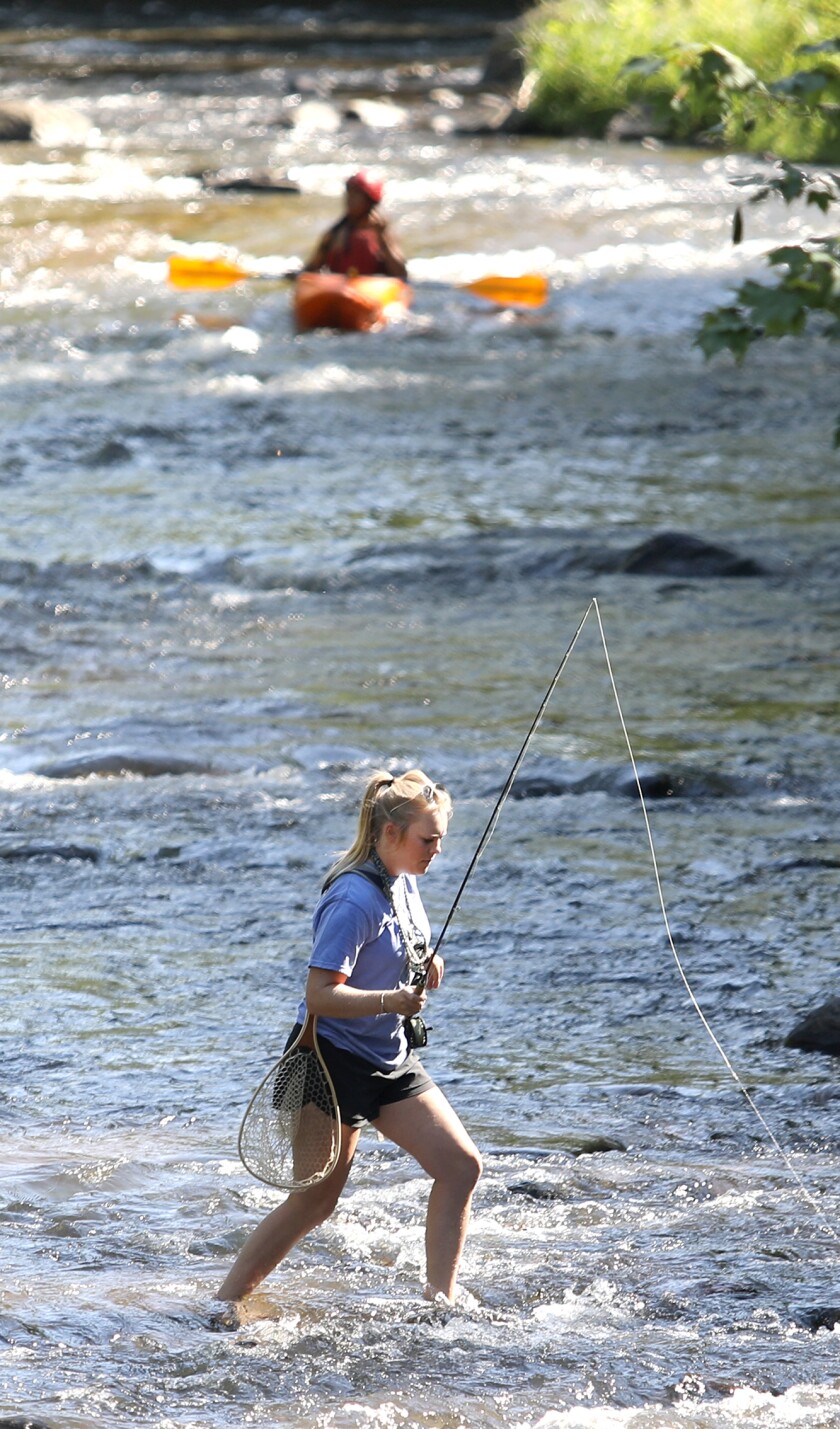 Maddie Kraemer takes a break from fly fishing as she walks over to the bank of the Brule River