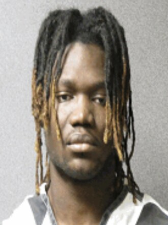 A mugshot of a man with braids.