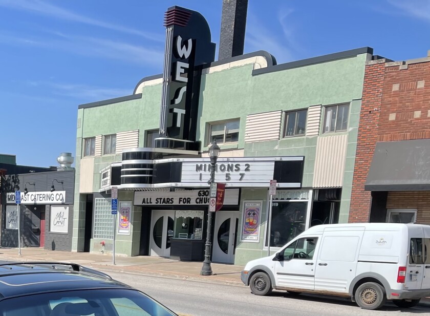 West Theatre is seen from street view on bright, sunny day with green stucco exterior and vertical marquee reading "WEST." "Minions 2" is playing.