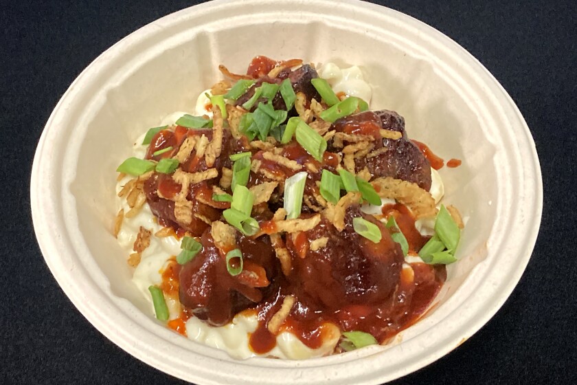 Macaroni and cheese served with burnt ends and crispy fried onions.