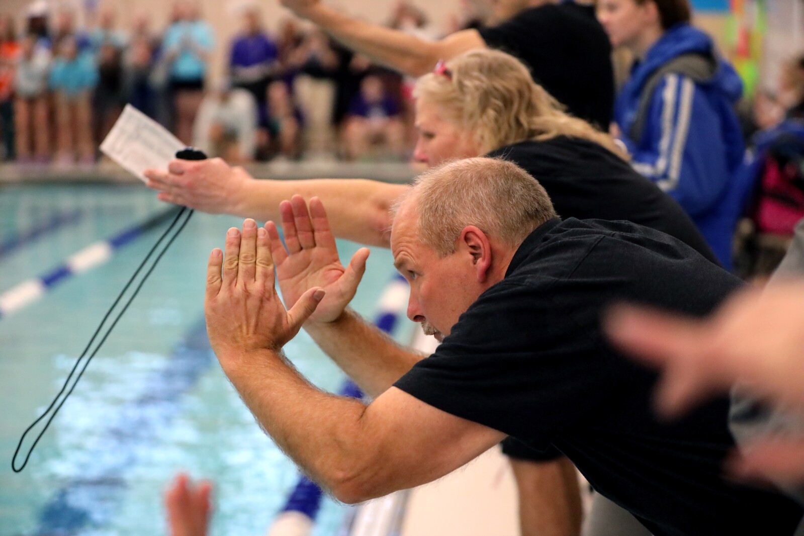Coaches cheer from the side of the pool.