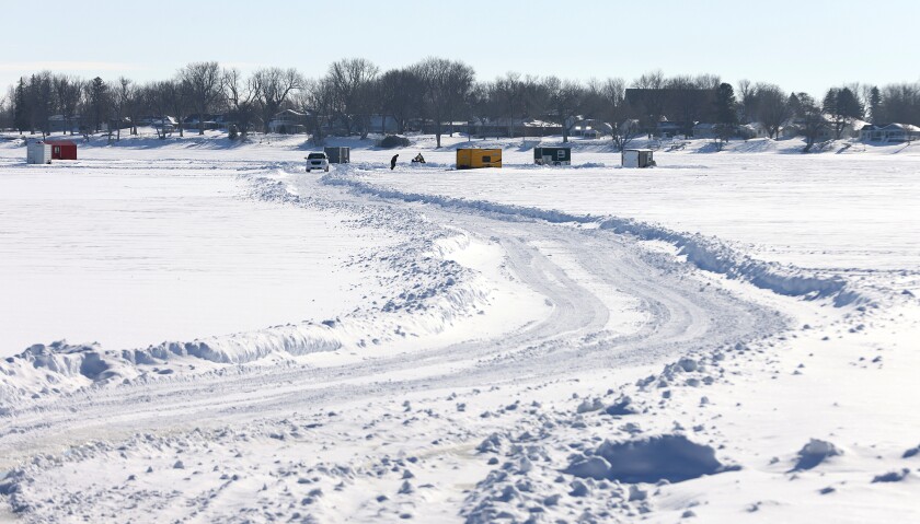 A fisherman checks his fish house as a four-wheeler pushes snow off the main trail on Lake Okabena in Worthington Thursday, Jan. 5, 2023.