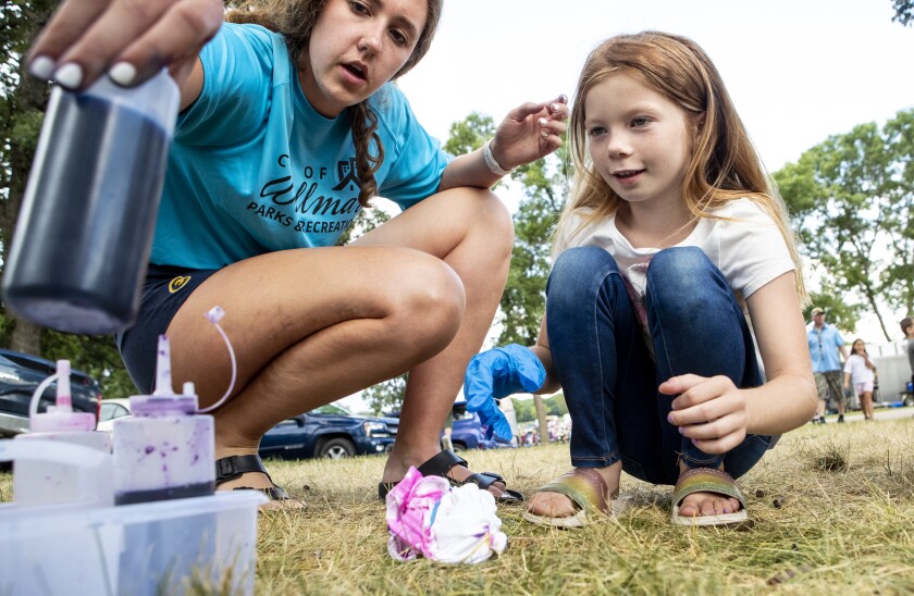 Willmar Parks and Recreation worker Abby Volk, from left, helps Brynlee Kottke, 7, tie dye a t-shirt during Rockin' Robbins at Robbins Island Regional Park in Willmar on Tuesday, July 26, 2022.