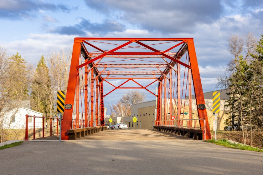 Red steel beams stretch up and over a short bridge.