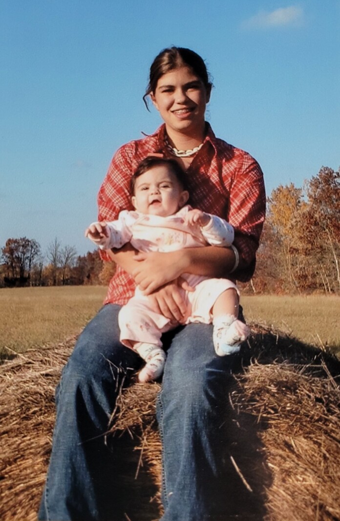 Young mom and baby pose on a hay bale