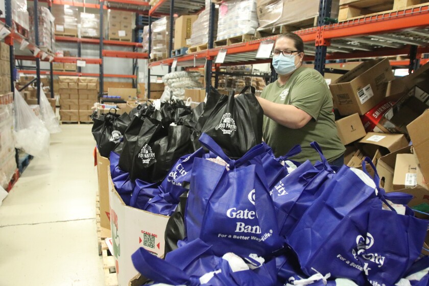 A woman loads packed, reusable grocery bags into pallet boxes.