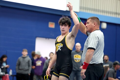 Ref holds up hand of winning wrestler.