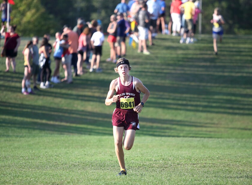 Solon Springs' Isaac Dickenson (6941) looks at the clock as he nears the finish line of the John Woodbury Invitational