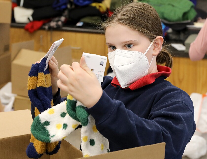 Fifth grader Addison Beck pulls out socks from a box of donations