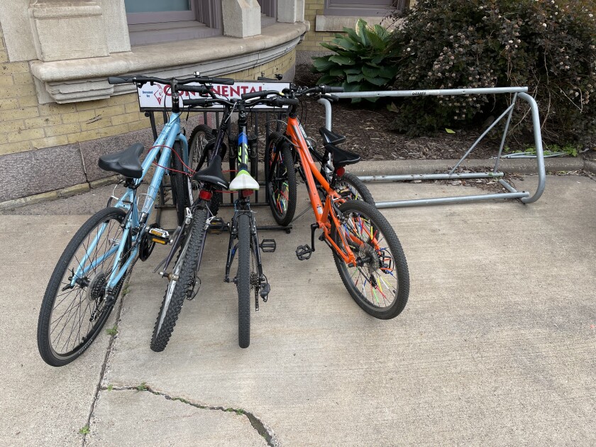 Four bicycles crowd a bike rack marked with the word CONTINENTAL, as another rack lacking vertical bars stands empty nearby.