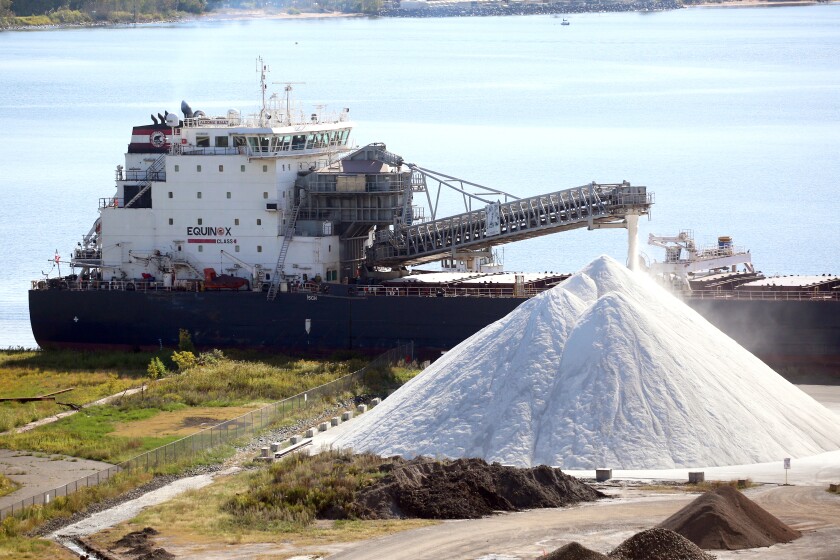 A ship docked and unloading salt onto shore.