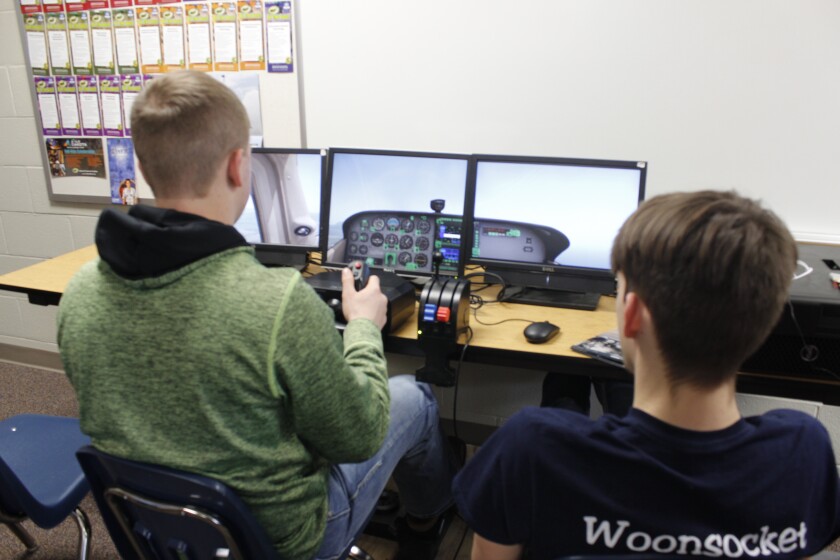 Aviation students at Woonsocket High School Wesley Linke, 17, left, and Malachi Bruce, 17, practice their pilot skills utilizing a realistic flight simulation software program during class last week. (Sheila Slater / Republic )