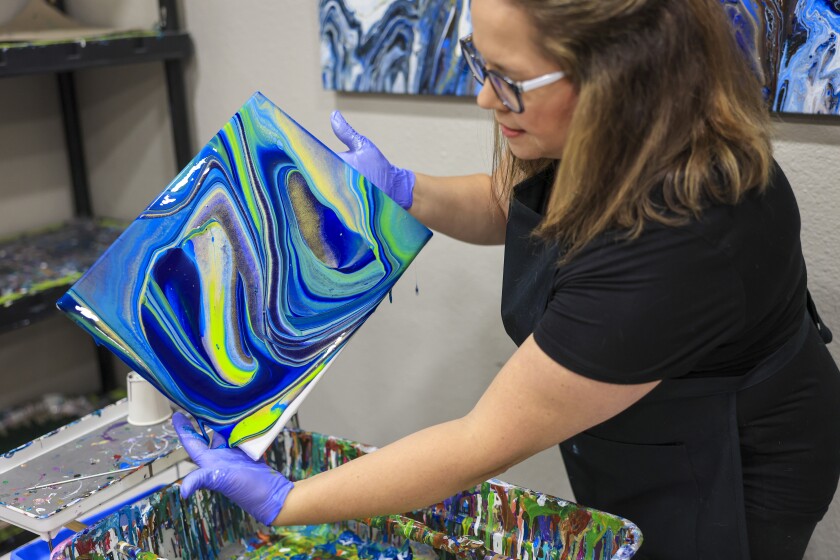 woman create fuid art work using paint