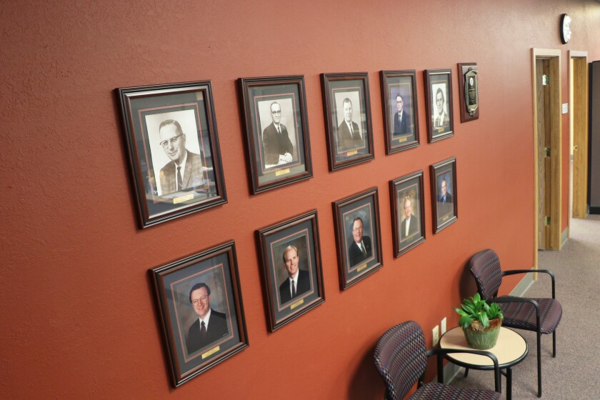 An office waiting room includes photos of all of its ten political appointees who have headed the Farm Service Agency in North Dakotas since 1954. All were men.