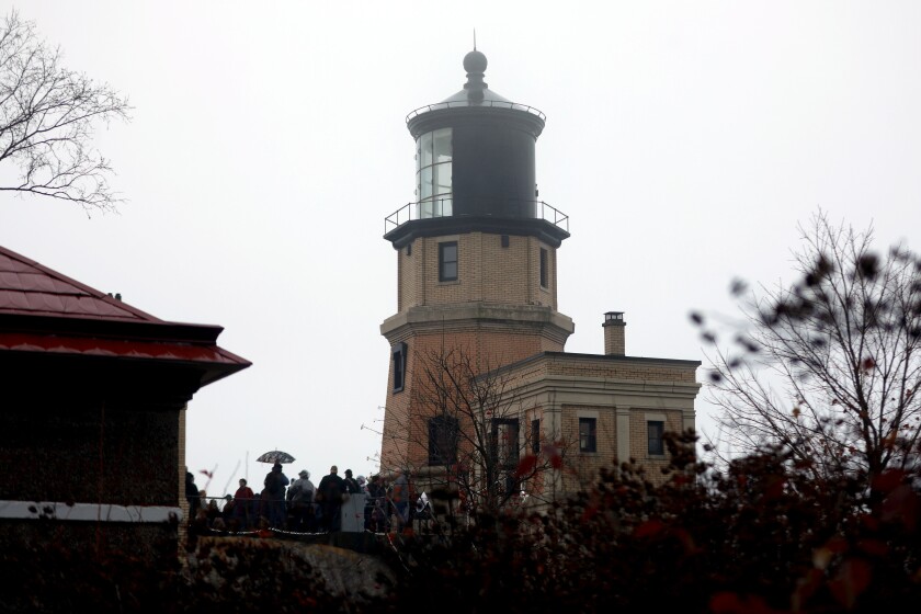A lighthouse in the background behind vegetation.