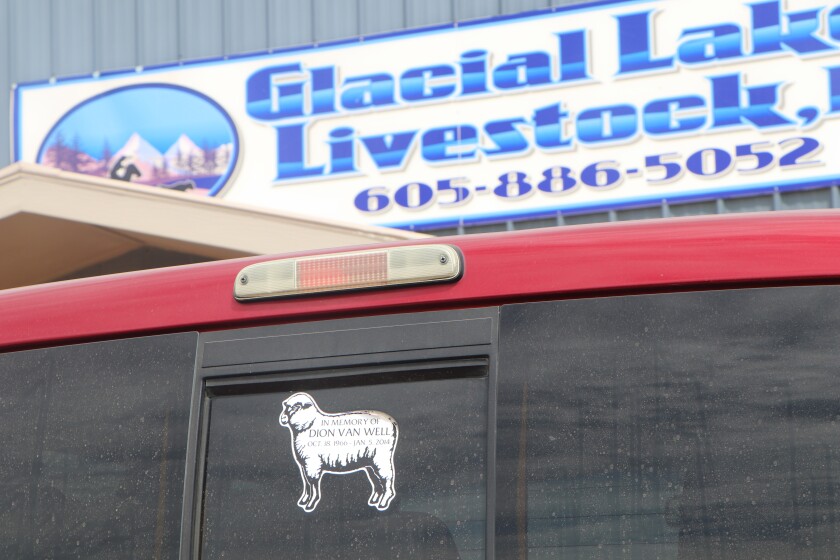 A decal on a truck, honoring a sheep industry giant, is parked in front of the Glacial Lakes Livestock sale barn, an important regional cattle industry player.