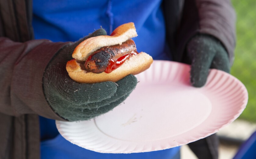 Senior Jordyn Tayloe eats a hot dog with a gloved hand due to the cold temperature at the homecoming tailgate Friday, Sept. 28, 2018, at Pequot Lakes High School.