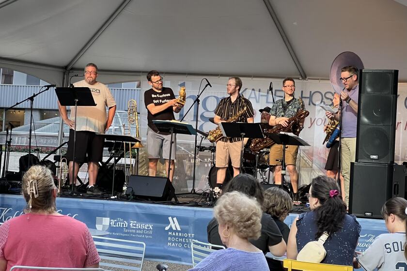 The Loud Mouth Brass band members standing on a public stage.