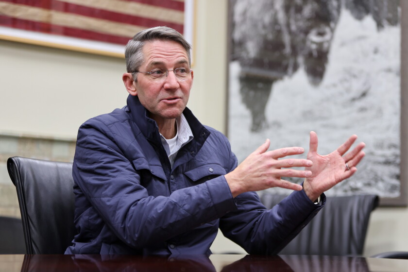 Drew Wrigley gestures while seated in a conference room