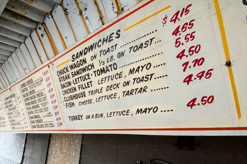 Handmade wooden signs list prices of burgers and sandwiches.