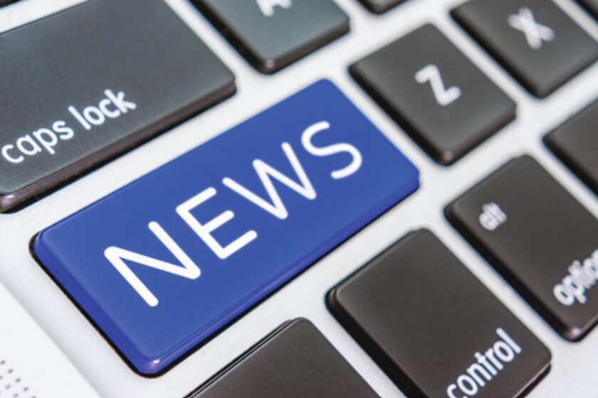 A computer keyboard with a "news" button on it in blue.