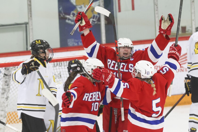 Girls hockey players in red, white and blue uniforms compete against players in black yellow and white uniforms on an indoor ice sheet.