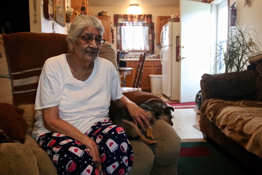 A woman with gray hair sits in an armchair with her eyes closed.