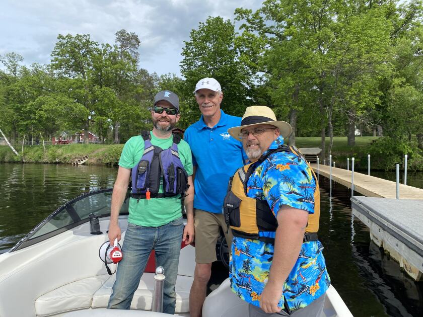 Three men stand on a boat.