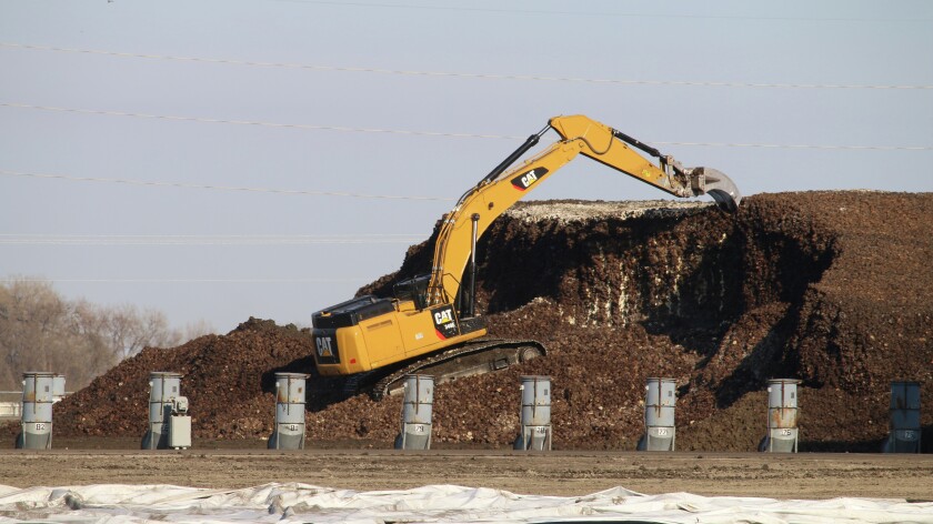 A worker removes white plastic over deep-freeze beets at the Minn-Dak Farmers Cooperative factory yard on April 22. Minn-Dak crews will use a "groomer" to remove up to a foot of black degraded material, to get to the beets below, which remain frozen. Photo taken April 22, 2016, at Wahpeton, N.D. (Forum News Service/Agweek/Mikkel Pates)