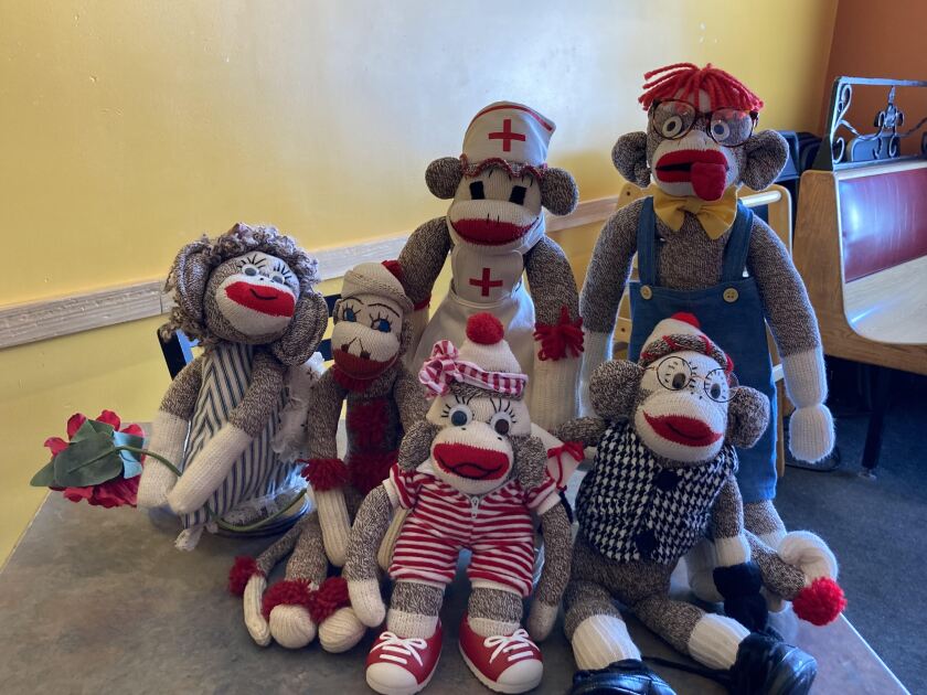A collection of six sock monkeys on a table.
