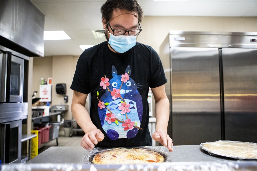 David Chanthakoune wraps up a pizza with saran wrap for Meals on Wheels at West Central Industries on Friday, May 20, 2022.