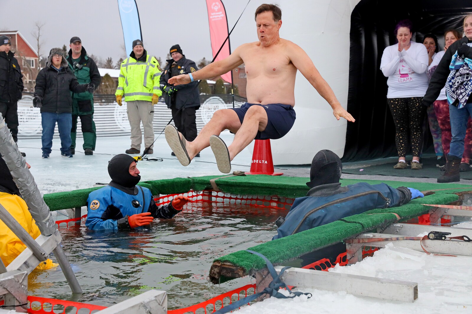 People jump into the water during the Polar Plunge event on Pelican Lake.