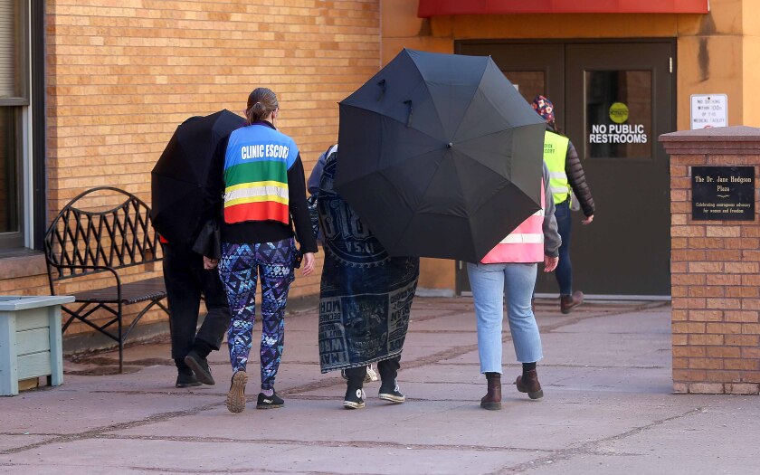 escorts surround a patient entering a building