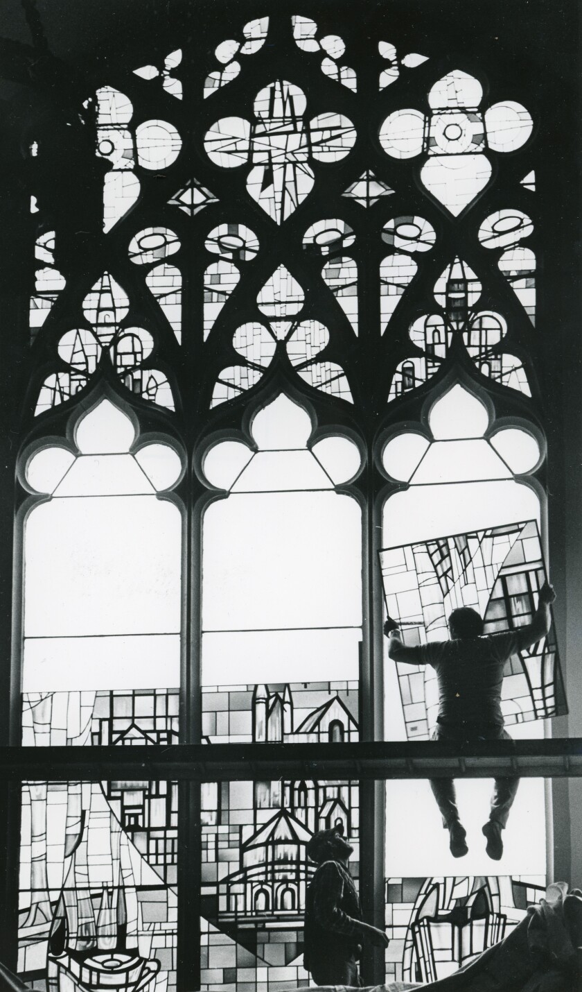 Jerry Bork sits on a ledge, holding a new stained glass window, ready for installation at Pilgrim Congregational Church in October 1979.