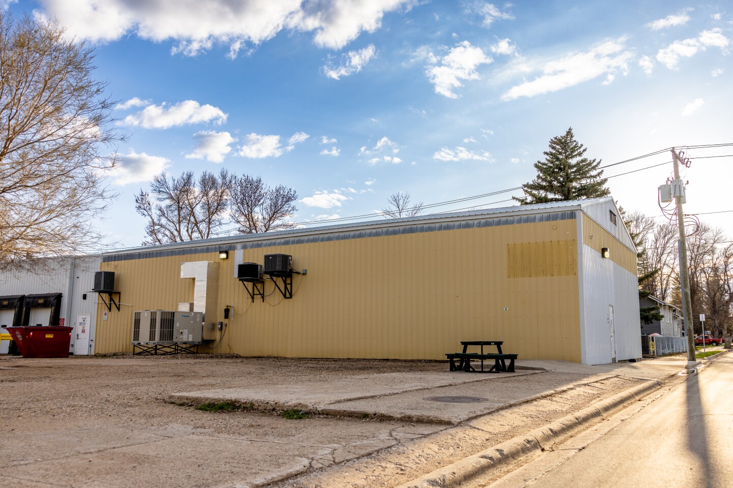 A yellow tin building with air conditioning units on the side.