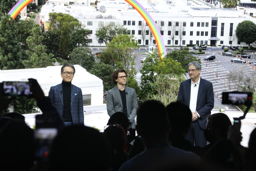 Three men stand in front of a crowd of people at the CES show.