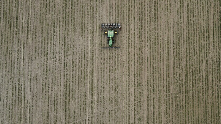 The aerial shot of a John Deere tractor pulling a planter through a field planted in cover crops.