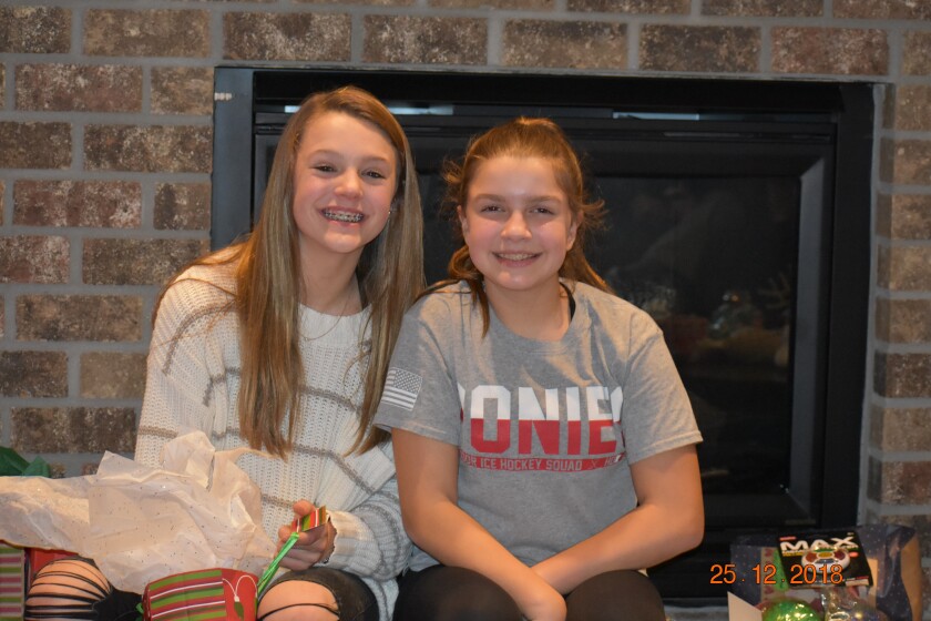 Two girls sit next to each other and smile.