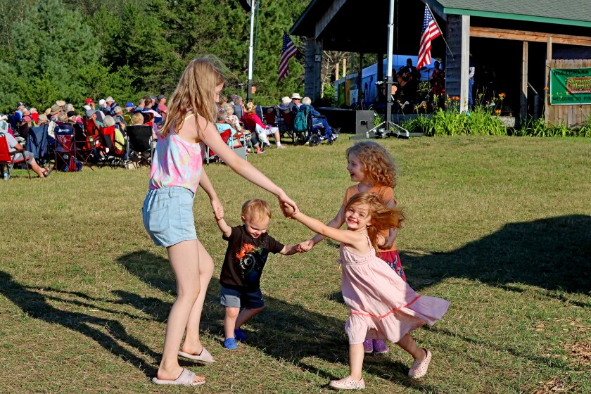 Kids dance to bluegrass music being played by in the background.